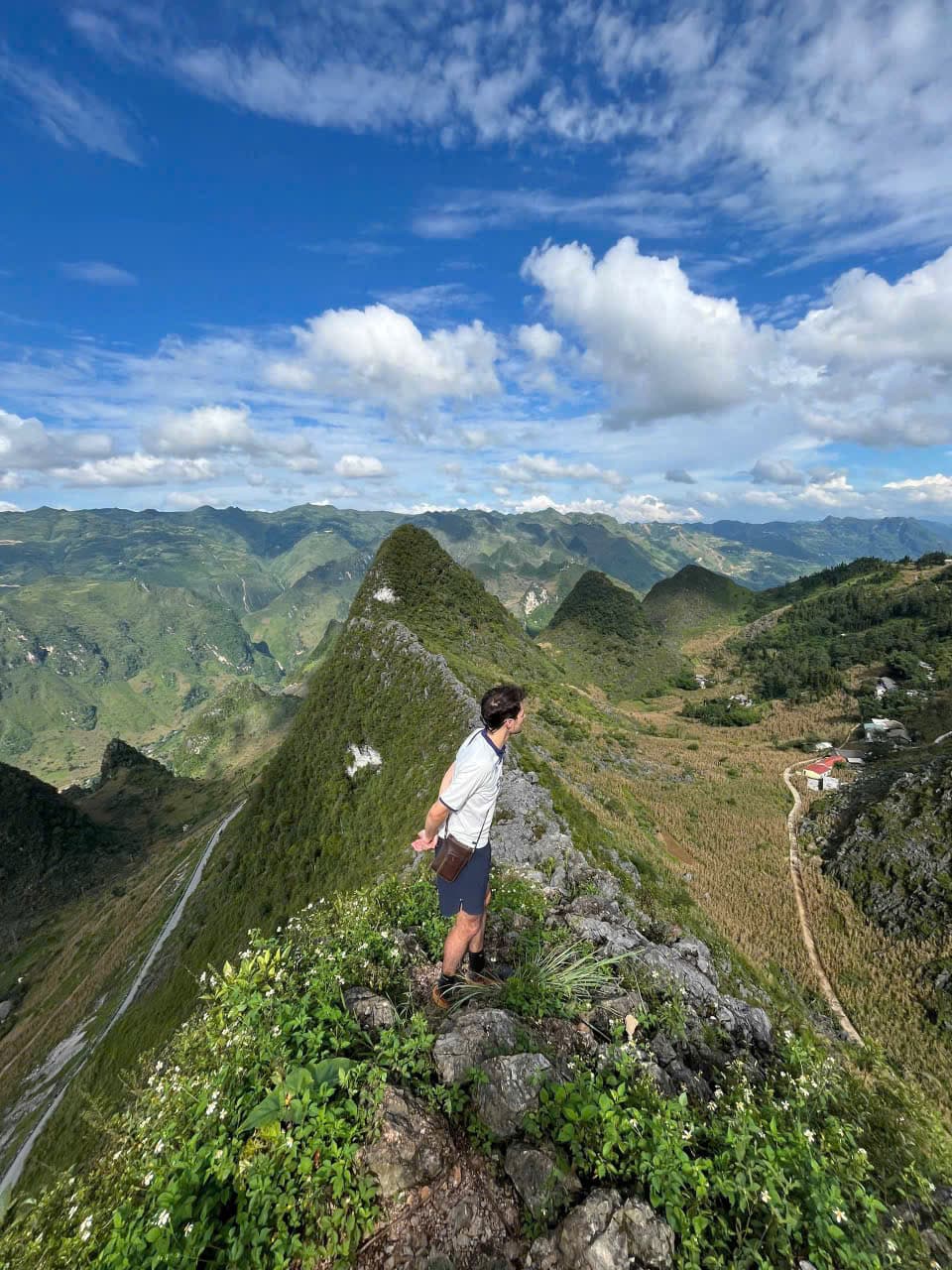 Traveler standing at a mountain viewpoint in Ha Giang with Vietnamese flag monument