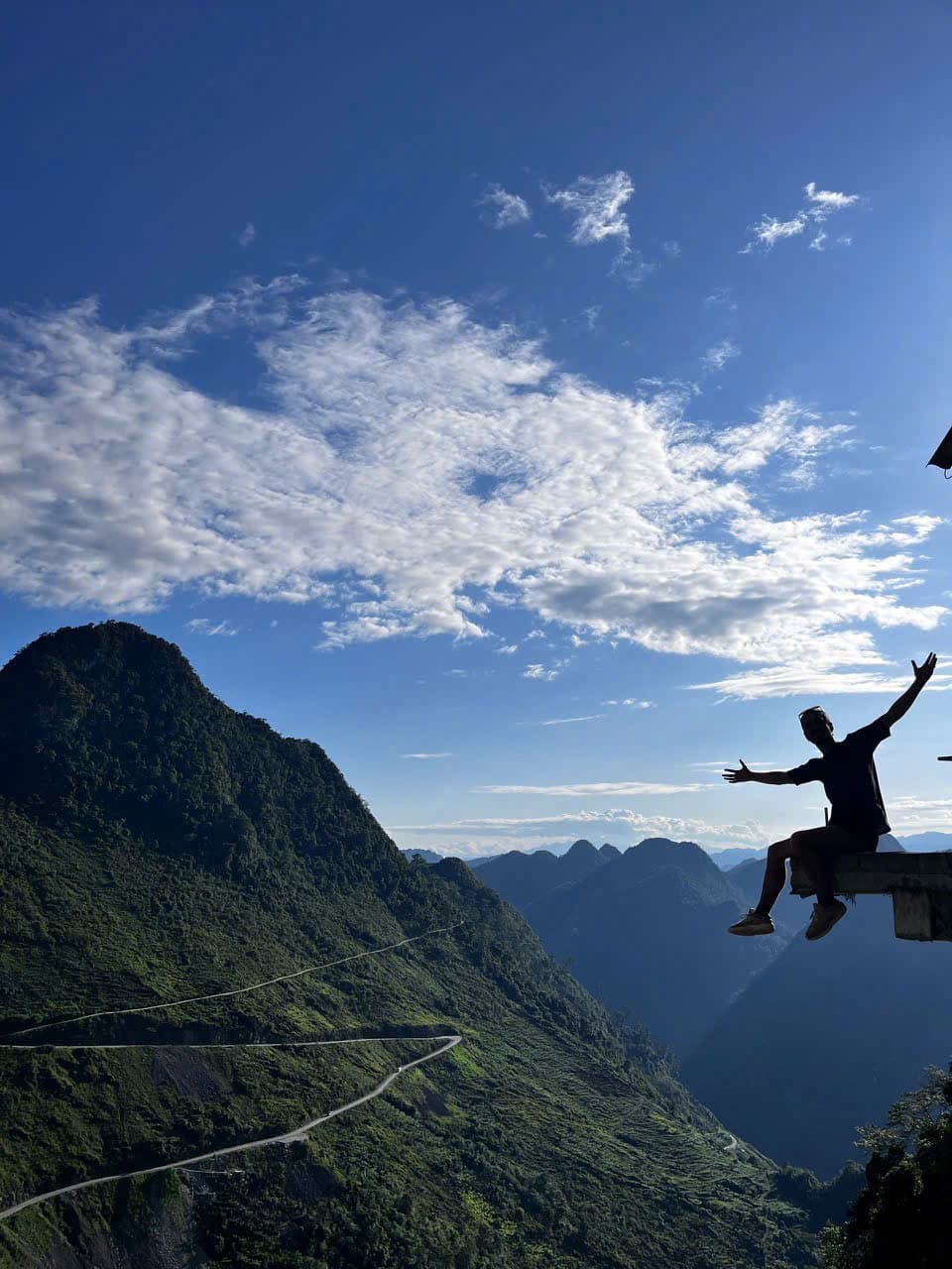 Traveler standing at a mountain viewpoint in Ha Giang with Vietnamese flag monument
